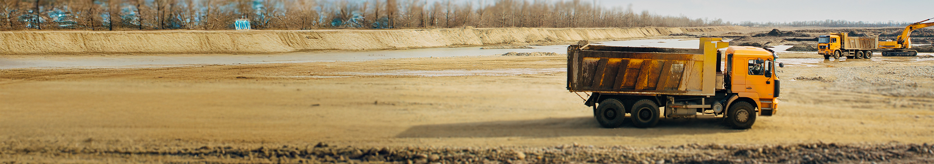 Dump truck equipped with construction truck tires operating at a muddy construction site alongside excavators.