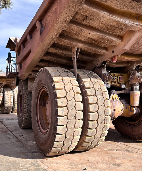 Close-up of M-RIGID tyres on a rigid dump truck, designed for durability, stability, and high load capacity in mining operations.